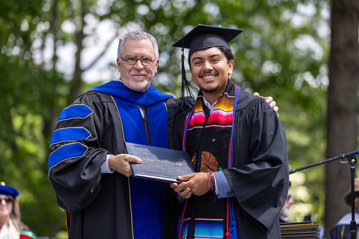 A student smiles with the president of the college at commencement.